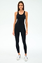 A woman faces forward against a white background, wearing SPLITS59's Ella High Waist Airweight 7/8 leggings in Black/White, a black sleeveless athletic top, and white sneakers.
