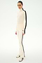 Wearing the SPLITS59 Jackson Rib Full Length Turtleneck in Creme/Black, this person pairs the cream modal blend top featuring black side stripes with matching pants and cream sneakers, standing against a light background.
