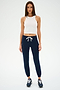 An individual stands against a plain background wearing the Kiki Rib Crop Tank in white by SPLITS59, paired with navy joggers and sneakers.