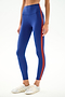 A person wears SPLITS59 Clare High Waist Rigor 7/8 - Cobalt/Terracotta leggings with white sneakers, standing against a plain white background.