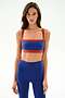 A woman faces forward in SPLITS59 Monah Rigor Bra - Cobalt/Terracotta and matching leggings against a plain light background.