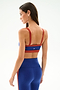 Woman in the SPLITS59 Monah Rigor Bra - Cobalt/Terracotta and matching high-waisted leggings, standing with her back to the camera against a plain background.