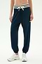 Model wears SPLITS59 Andie Oversized Fleece Sweatpant W/ Stripe in Indigo, featuring a white drawstring and striped waistband, paired with white sneakers against a plain light background.