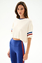 Model wearing the Djuna Oversized Crop Jersey Tee - Creme/Cobalt by SPLITS59 with high-waisted blue leggings, standing against a plain background.