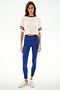 Woman in a Djuna Oversized Crop Jersey Tee - Creme/Cobalt by SPLITS59, blue high-waisted spandex leggings, and silver sneakers against a white background.