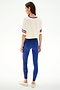 Woman wearing the SPLITS59 Djuna Oversized Crop Jersey Tee - Creme/Cobalt, blue leggings with red side stripes, and white sneakers, facing away against a white background.