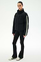 A person wearing the SPLITS59 Maeve Puffer Jacket in Black/Creme—crafted from 100% nylon with distinctive white sleeve stripes—paired with black flared pants and white sneakers, stands against a plain white background.