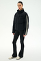 A person wearing the SPLITS59 Maeve Puffer Jacket in Black/Creme—crafted from 100% nylon with distinctive white sleeve stripes—paired with black flared pants and white sneakers, stands against a plain white background.
