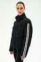 A woman models the SPLITS59 Maeve Puffer Jacket in Black/Creme, a 100% nylon jacket distinguished by two white stripes on the sleeve, standing against a plain light background.