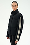 A woman models the SPLITS59 Maeve Puffer Jacket in Black/Creme, a 100% nylon jacket distinguished by two white stripes on the sleeve, standing against a plain light background.