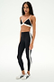 A person stands facing forward against a plain white background, wearing the SPLITS59 Sage Rigor Bra in Black/White.