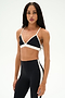 A person stands against a plain white background wearing the SPLITS59 Sage Rigor Bra in black and white, paired with matching high-waisted leggings, both crafted from a comfortable blend of nylon and spandex.