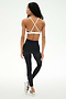 A woman stands against a white background wearing the SPLITS59 Sage Rigor Bra in Black/White, paired with black nylon leggings featuring a white stripe and white athletic shoes.