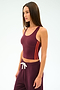A woman wears the SPLITS59 Ella Airweight Tank in Dark Cherry/Valencia, featuring orange side stripes and matching pants with a white drawstring, made from stretchy nylon spandex, against a plain light background.