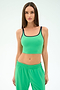 A woman with long straight hair wears the SPLITS59 Cait Rigor Bralette in Grass/Indigo, paired with matching green pants, standing against a plain light background.