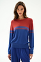 A woman wears the SPLITS59 Anna Knit Pullover - Cobalt/Terracotta, featuring long sleeves and a red top half with blue bottom half and thin red stripes, against a white background.