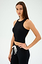 A person with long hair poses against a plain background wearing the SPLITS59 Kiki Rib Crop Tank in black, paired with black pants featuring a white drawstring.