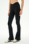 Wearing the SPLITS59 Raquel Crossover Supplex Flare in Black—high-waisted, flared leggings crafted from 4-way stretch Supplex—a person stands against a plain white background in white sneakers with black stripes. Perfect for yoga, these crossover waist leggings deliver both comfort and style.