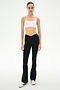 A woman stands facing forward on a plain white background, wearing a white sports bra, white sneakers, and the SPLITS59 Raquel Crossover Supplex Flare leggings in black, featuring a V-shaped crossover waistband and made from 4-way stretch Supplex fabric.