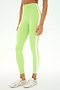 A person stands against a plain background wearing the SPLITS59 Clare High Waist Rigor 7/8 leggings in Limeade/White—a high-waisted style crafted from a soft nylon-spandex blend with a white side stripe—paired with white sneakers.