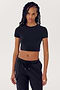 Person with long dreadlocks wearing a SPLITS59 Airweight S/S Crop - Black and black nylon pants, standing against a plain white background.