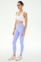 A person wears the SPLITS59 Airweight Bra with Ruching in white, light purple leggings, and white sneakers, standing against a plain light background.
