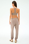 A woman faces away in cool weather workout style, wearing the SPLITS59 Andie Oversized Fleece Sweatpant in Latte with a taupe sports bra and beige sneakers with maroon stripes, set against a plain light background.