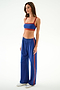 Woman wearing SPLITS59 Maxie Rigor Track Pant - Cobalt/Terracotta and a blue sports bra, standing against a plain white background.