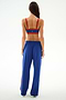 A woman faces away, wearing a red sports bra and SPLITS59 Maxie Rigor Track Pant - Cobalt/Terracotta, against a plain white background.