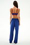 A woman faces away, wearing a red sports bra and SPLITS59 Maxie Rigor Track Pant - Cobalt/Terracotta, against a plain white background.