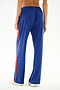 A person stands barefoot on a white background wearing SPLITS59 Maxie Rigor Track Pant - Cobalt/Terracotta, photographed from behind.