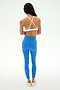 A person stands on a white background, facing away, wearing the SPLITS59 Sage Rigor Bra in Classic Blue/White with crisscross straps, paired with bright blue leggings made from stretchy nylon spandex fabric and white shoes.