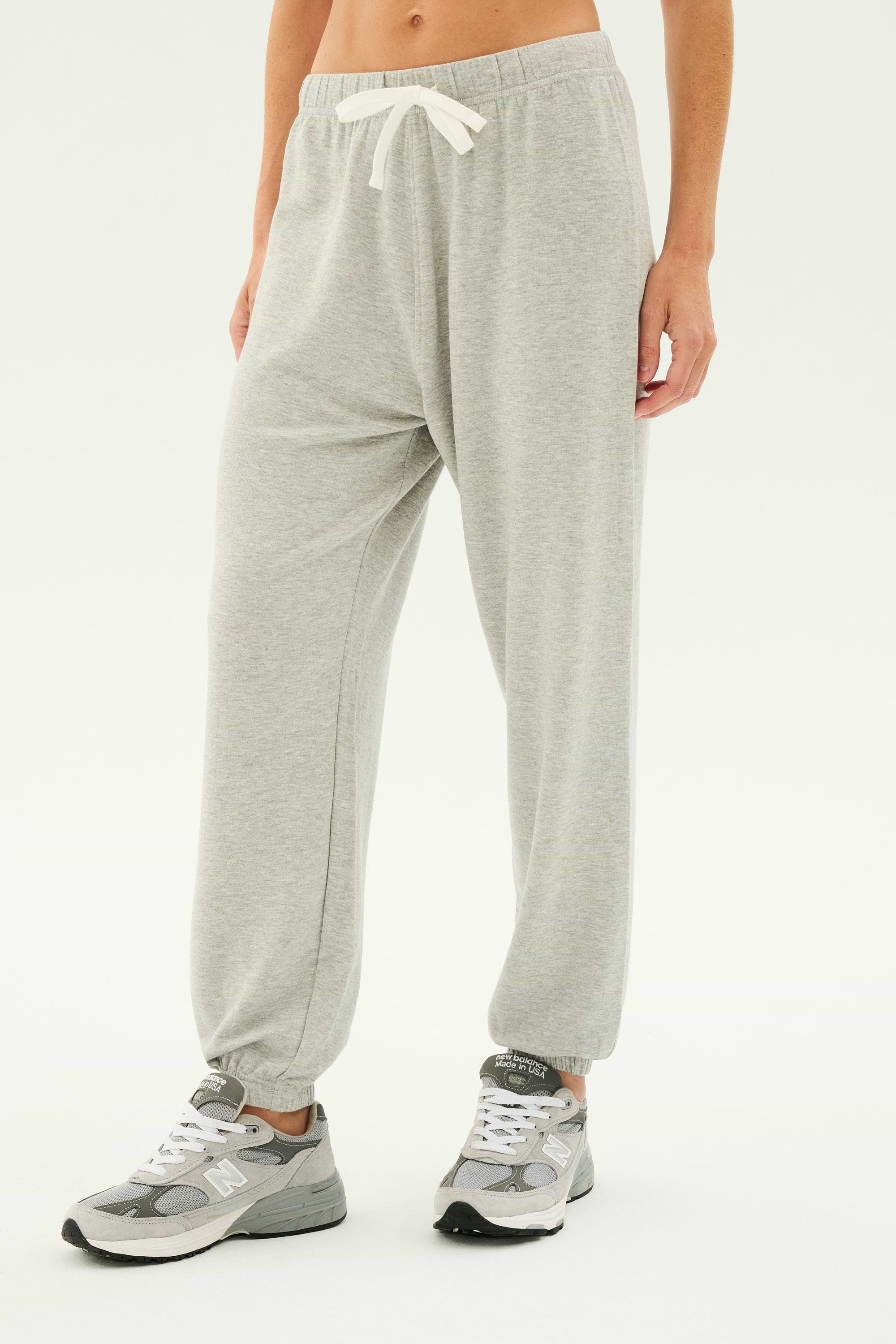 Person wearing SPLITS59 Andie Oversized Fleece Sweatpant in Heather Grey with a white drawstring and grey sneakers, ideal for cool weather workouts or warm-ups, standing against a plain background.