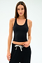A woman wears the SPLITS59 Ella Airweight Tank in Black/White and black drawstring pants, both crafted from a smooth nylon spandex blend, standing against a plain white background.