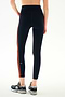 A person wearing SPLITS59 Ella High Waist Airweight 7/8 - Indigo/Valencia dark blue, high-waisted spandex leggings with vertical orange stripes and athletic sneakers.