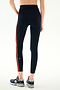 A person wearing SPLITS59 Ella High Waist Airweight 7/8 - Indigo/Valencia dark blue, high-waisted spandex leggings with vertical orange stripes and athletic sneakers.