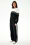Woman wears the SPLITS59 Anna Knit Pullover - Black/White with matching wide-leg track pants and white sneakers, standing against a plain white background.