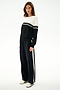 Woman wears the SPLITS59 Anna Knit Pullover - Black/White with matching wide-leg track pants and white sneakers, standing against a plain white background.