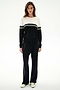 Woman standing against a white background, wearing the SPLITS59 Anna Knit Pullover - Black/White, black pants, and white sneakers.