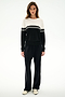 Woman standing against a white background, wearing the SPLITS59 Anna Knit Pullover - Black/White, black pants, and white sneakers.