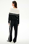 A woman faces away, wearing the SPLITS59 Anna Knit Pullover - Black/White with matching striped pants, both made of soft rayon fabric.