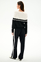 A woman faces away, wearing the SPLITS59 Anna Knit Pullover - Black/White with matching striped pants, both made of soft rayon fabric.