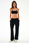 A person wearing a black sports bra and SPLITS59 Maxie Rigor Track Pant in black and white, paired with white sneakers.