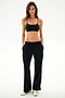 A person wearing a black sports bra and SPLITS59 Maxie Rigor Track Pant in black and white, paired with white sneakers.