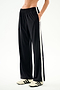 SPLITS59 Maxie Rigor Track Pant in black with a vertical white stripe down each side, worn with cream sneakers with black stripes.