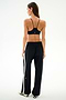 A woman seen from behind wearing a black sports bra and Maxie Rigor Track Pant - Black/White with a white side stripe.