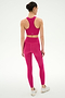 A person faces away, wearing the SPLITS59 Airweight High Waist 26" leggings in Sangria and a matching sports bra with white athletic shoes, set against a plain white background.