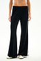 Model showcases SPLITS59 Heritage Velour Pant - Black/Creme, featuring a white side stripe and flared silhouette; image focuses on lower torso and legs against a white background.