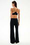 Woman stands with back to camera in black sports bra and SPLITS59 Heritage Velour Pant - Black/Creme, against a plain white background.