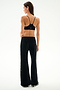Woman stands with back to camera in black sports bra and SPLITS59 Heritage Velour Pant - Black/Creme, against a plain white background.